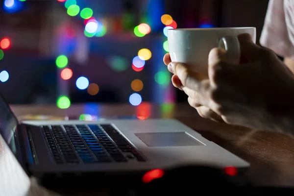 night time worker in office sitting at the table using laptop and drink coffee  f