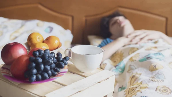 Matin petit déjeuner nourriture sur le plateau en bois dans le lit de l'hôtel à côté de la personne qui dort f — Photo