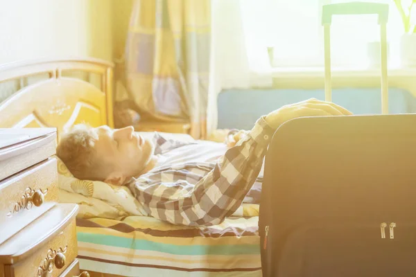 Reiseunternehmer ruhen sich im Hotelzimmer aus, liegen im Bett neben dem Kofferraum. — Stockfoto