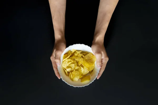 Vista dall'alto delle mani che tengono un piatto bianco con patatine snack f — Foto Stock