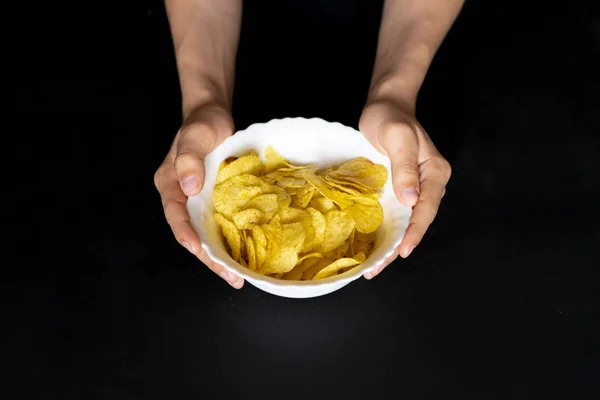 Bovenaanzicht van de handen met een witte plaat met chips snacks f — Stockfoto