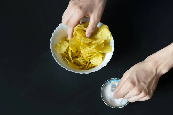 Mão despeje sal no prato com batatas fritas lanches f — Fotografia de Stock