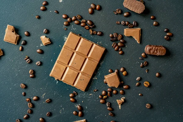 Barra de chocolate con granos de café en la mesa oscura plana poner f — Foto de Stock