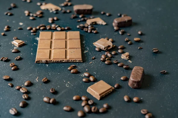 Barra de chocolate con granos de café en la mesa oscura plana poner f — Foto de Stock