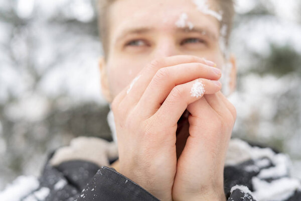 close up man portrait warm up and heating hands near mouth outdoors on a winter day f