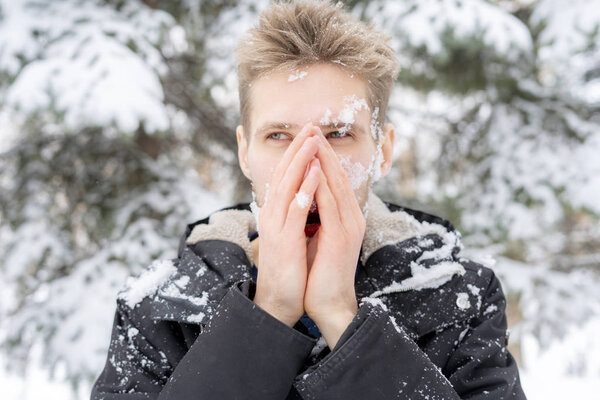 close up man portrait warm up and heating hands near mouth outdoors on a winter day f