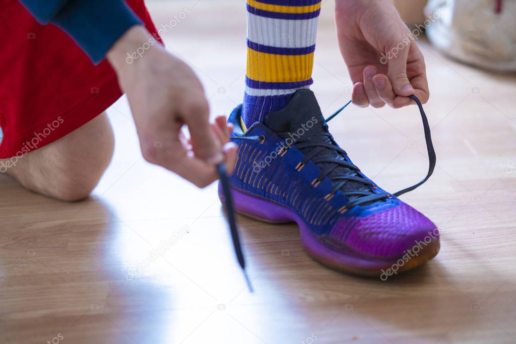 cropped view of sportsman hands tie shoelaces of sneakers at the locker room i