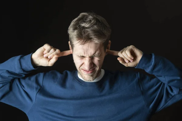 Jovem estressado masculino protegendo seus ouvidos de ruídos irritantes — Fotografia de Stock