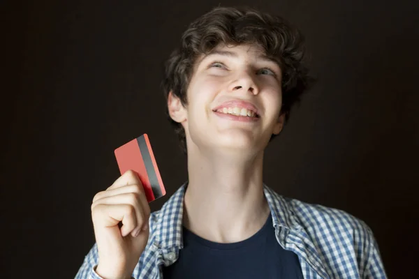Nuori mies pitää luottokorttia ja unelma missä viettää rahaa f — kuvapankkivalokuva