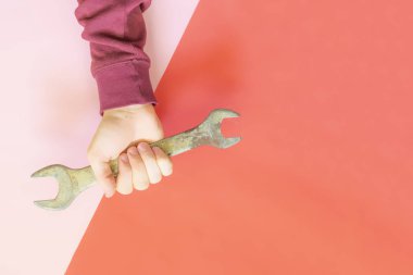 renk arka plan f üzerinde bir İngiliz anahtarı tutan kişinin el üstten görünüm