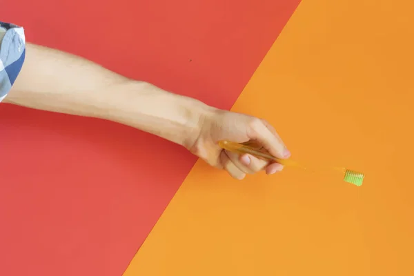 Vista superior de la mano de la persona sosteniendo un cepillo de dientes sobre el fondo de color f — Foto de Stock