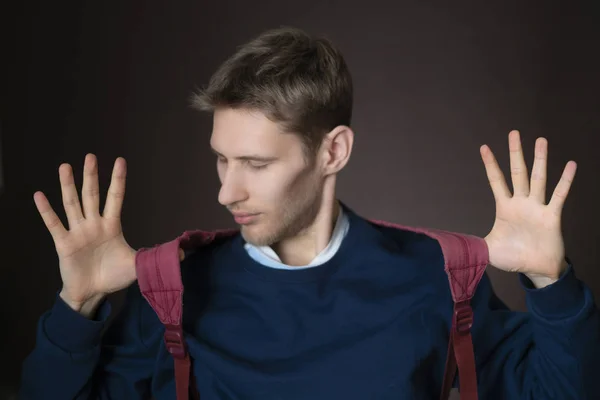 Jeune beau mâle souriant avec sac à dos dans occasionnel isolé sur fond sombre f — Photo