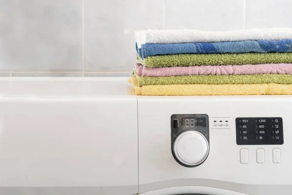 Σωρό από πολύχρωμες πετσέτες Βάλτε στο πλυντήριο σε πλυντήριο ρούχων και πίνακας β — Φωτογραφία Αρχείου