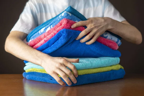 close up hands lay down stack of clean towels on table f