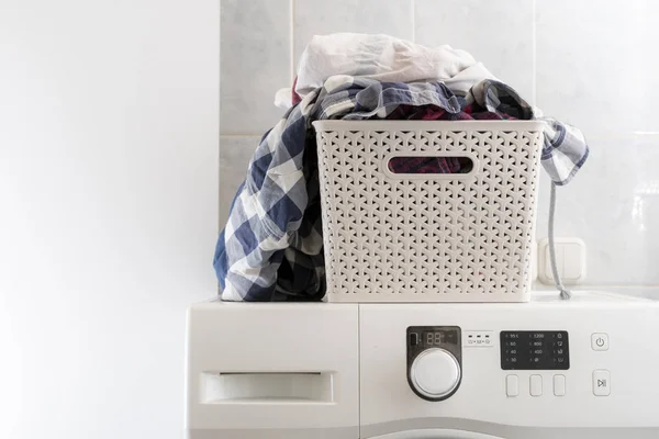 Pakaian kotor dalam keranjang plastik di binatu berbaring pada mencuci mashine dan meja b — Stok Foto
