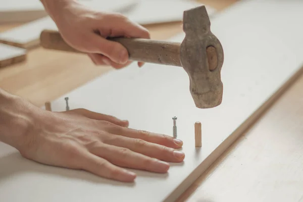 Nahaufnahme Mann montiert nagelneue Möbel mit dem Hammer auf dem Holzboden n — Stockfoto