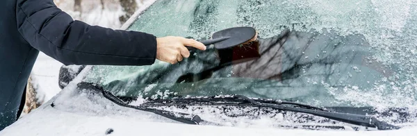 Hand cleaning up windscreen from snow and ice in a winter season — Stock Photo, Image