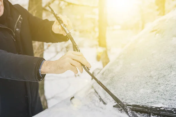Uomo che regola e pulisce i tergicristalli dell'auto con tempo nevoso b — Foto Stock