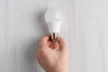 Beyaz arka plan ve b tutan el yalan ampul