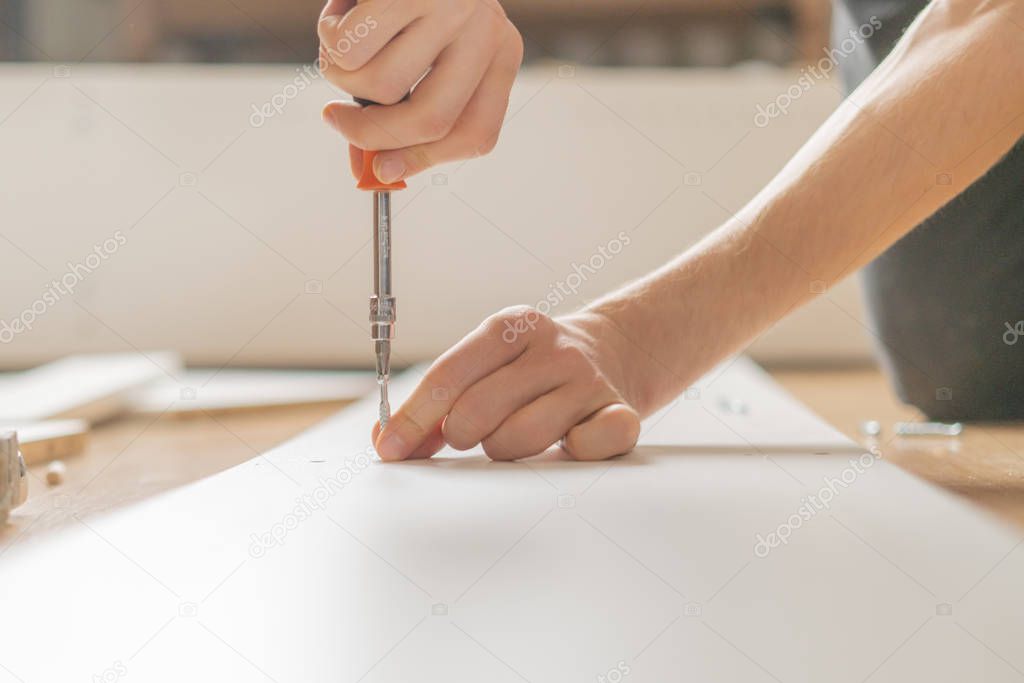 close up man assembling new furniture with a screwdriver b