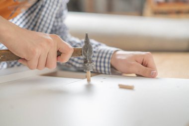 adam ahşap zemin n üzerinde çekiç ile yepyeni mobilya montaj kapatın