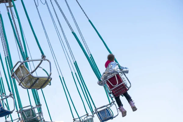 Criança se divertindo montando em um carrossel cadeia no parque de diversões b — Fotografia de Stock