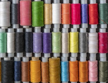 Bir demet renkli dikiş ipliği koyu arkaplanda izole bir şekilde duruyordu.