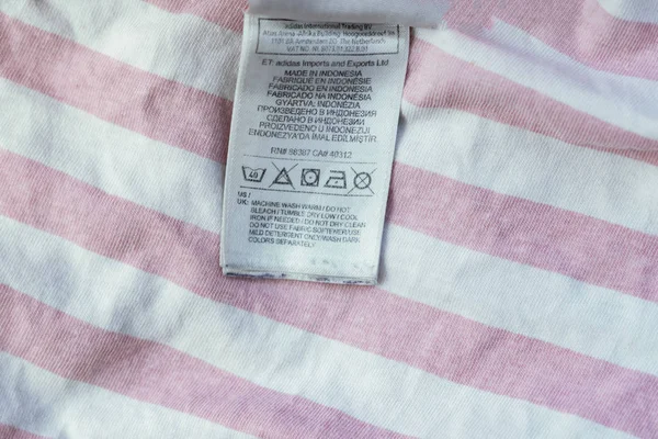 Close up brand new clothes instruction before washing. laundry tag b — Stock Photo, Image