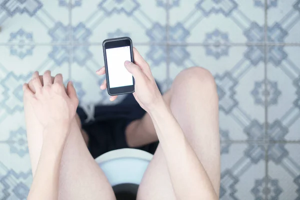 Kaukasischer Mann sitzt auf Toilette und benutzt sein Handy-Gadget — Stockfoto