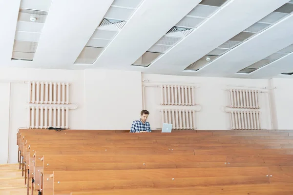 Joven estudiante sentarse solo en enorme sala de conferencias b — Foto de Stock