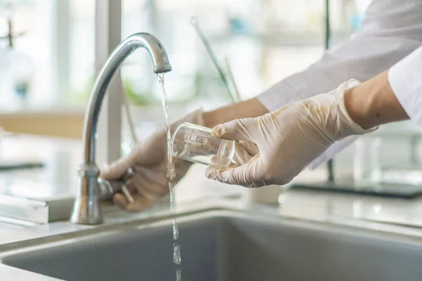 Wetenschapper wassen bekerglas van giftig zuur na experimenten b — Stockfoto