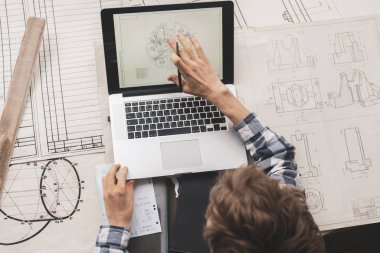 genç erkek mimar veya kağıt çizimler ived ve bir dizüstü bilgisayar b ile çalışmak