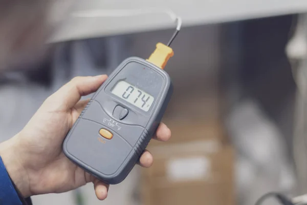 Worker in blue uniform hold electric miltimeter to check voltage b — Stock Photo, Image