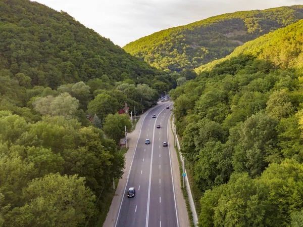 Aerial view of wide highway between the mountains covered with green woods b — Stock Photo, Image