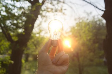 kişinin ilk kişi görünümü doğa dışında ampul tutun, onun aracılığıyla bir güneş ışığı ile enegry kavramı