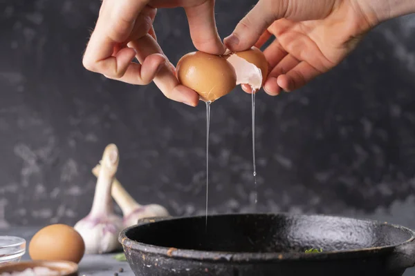 Pessoas mão segurar ovo rachado e despeje uma gema de ovo e proteína em uma frigideira para cozinhá-lo, estilos rústicos — Fotografia de Stock