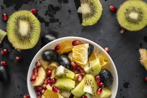 Salada de frutas com frutas tropicais exóticas maduras picadas em cubos, laranja, kiwi, banana, uvas, romãs — Fotografia de Stock