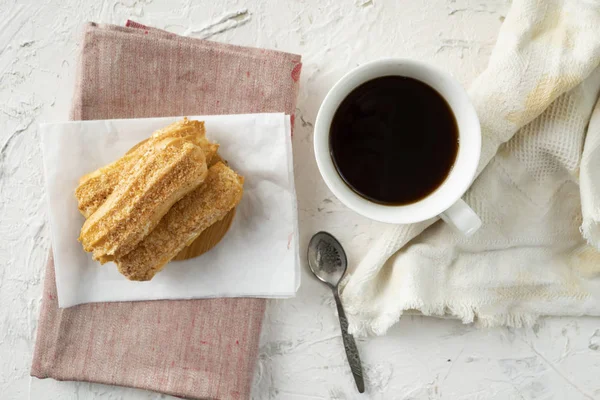 Merienda de la mañana con café y eclair cremoso en una mesa con mantel blanco, desayunos de negocios — Foto de Stock
