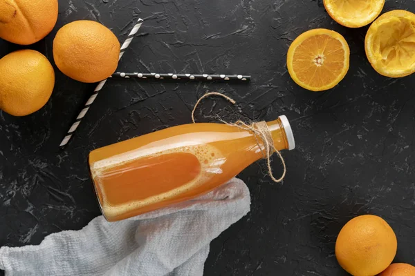 Üvegpalack egy facsart narancslevet, szeletelt fél narancs körül — Stock Fotó