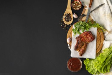 Izgara ribeye sığır eti biftek, ot yaprakları ve baharatlar etrafında, metinler için kopya alanı ile üst görünümü