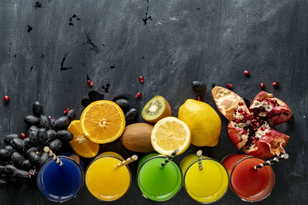 Vista superior de la variedad de zumos frescos, diferentes frutas alrededor, copiar el espacio para su texto en una mesa negra —  Fotos de Stock