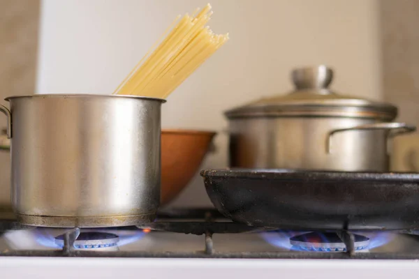 Dolgozó obrn eith égő gáz-és serpenyőben forrásban lévő ízletes étel van, otthon mármit — Stock Fotó