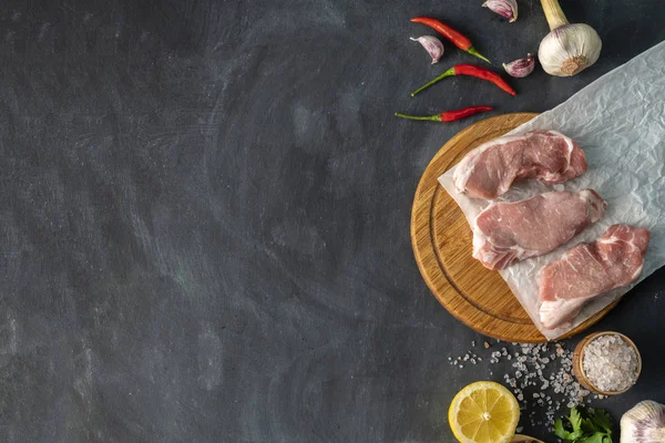 Widok z góry na plasterki surowego mięsa na drewnianej deski do krojenia z składników do gotowania, takich jak przyprawy cytrynowe i herbss — Zdjęcie stockowe