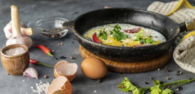 baharatlı omlet veya pastırma, sarımsak ve biber ile bir tavada omlette, tablolar etrafında malzemeler