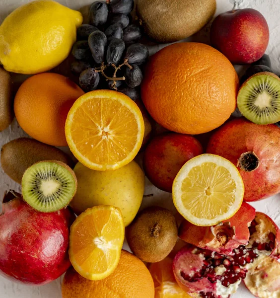 Абстрактний фон зі свіжими органічними фруктами, такими як нарізані апельсиновим виноградом ківі та гранатами — стокове фото