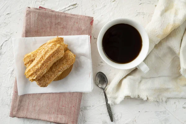 Morning snack with coffee and creamy eclair on a table with white tablecloth, business breakfasts — Stock Photo, Image