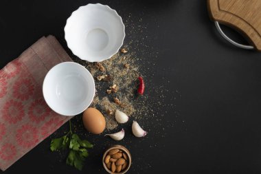 siyah masa üzerinde boş beyaz seramik plaka, yemek pişirmek için taze malzemeler, karabiber, sofra