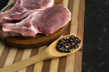 dilimleme tahtası üzerinde ham domuz filetosu, baharat ve biber ile tahta kaşık, yağ abur cubur, pişmemiş
