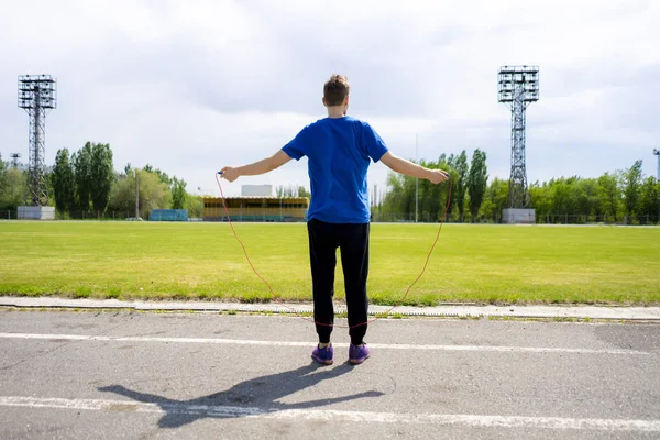 Atleta masculino esportista praticar com corda de salto nos estádios ao ar livre, aumentar a resistência — Fotografia de Stock