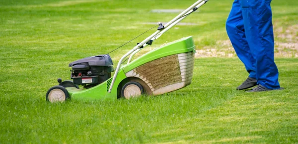 Jardinier travailleur coupe herbe avec tondeuse dans les champs de pelouse arrière — Photo